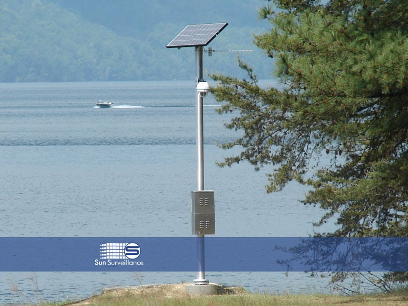 A solar-powered surveillance sytems in use near a lake.